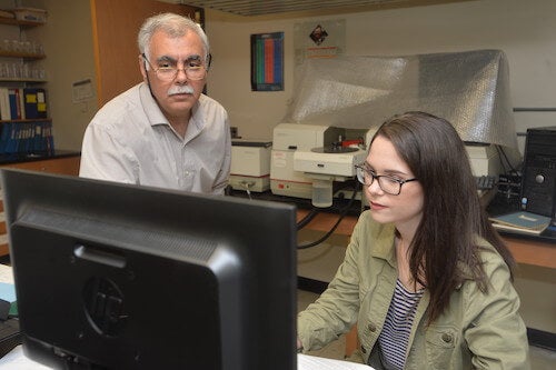 Student and faculty member look at a computer in a classroom