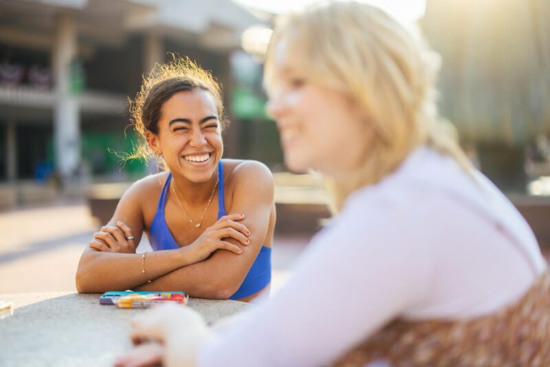 two students talking outside the Memorial Student Center and smiling