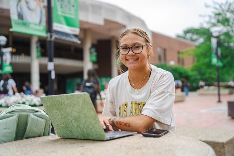 student working on a laptop outside the Memorial Student Center