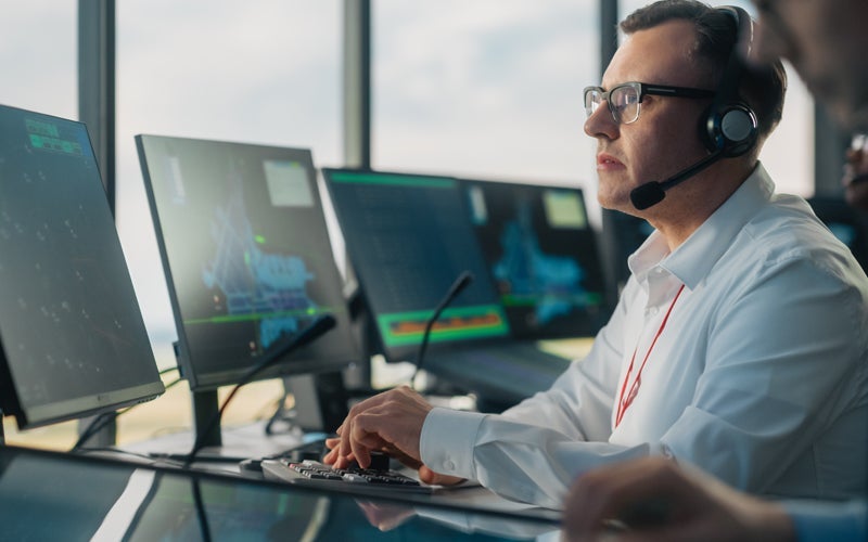Aircraft Dispatcher works on a computer from an airport tower.