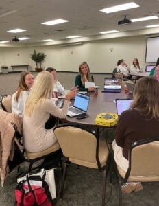 a group of students and educators conversing and presenting at a round table at Marshall University