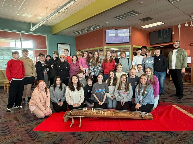 large group of students at a HATS event with a project and smiling at the camera