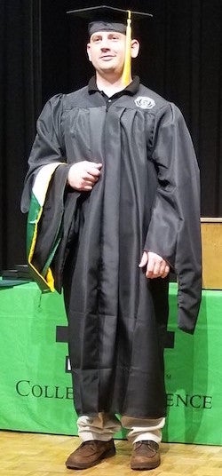 Professor Lawrence places a graduation hood on a student.