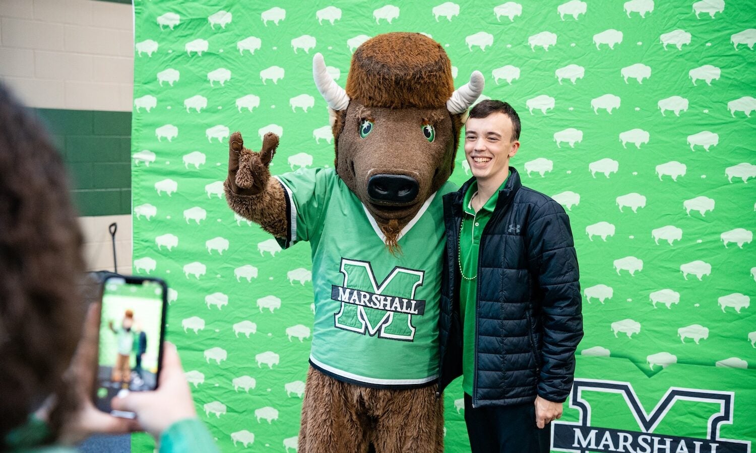 student smiling with marco in front of a Marshall background