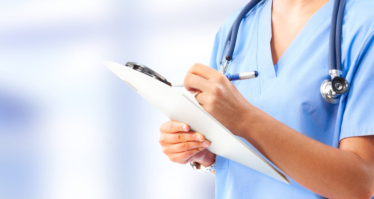 A nurse writes on a clipboard