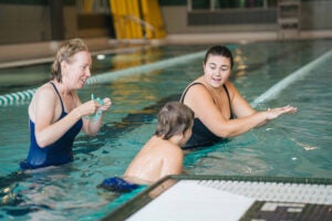 Volunteers with the Safe Swim for All program help a student learn to swim