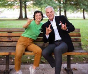 Michaela Marshall sits on a bench smiling with Marshall University president Brad D. Smith