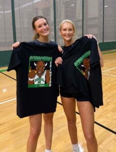 Two students smile while holding up their intramural champion t-shirts