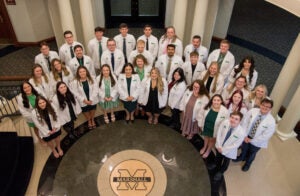 Marshall University School of Pharmacy students gather together for a photo wearing their white coats