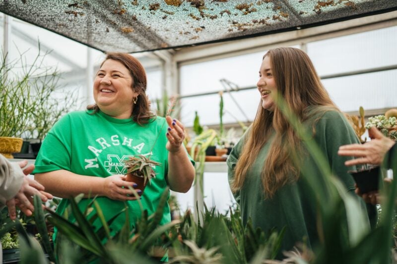professor and student laughing in the greenhouse