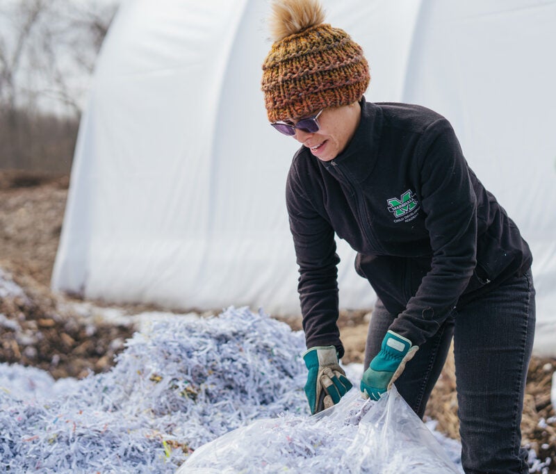 An employee spreads shredded paper at Marshall University's Composting Facility