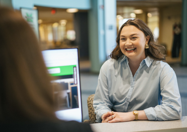 woman at desk talking to person on a computer