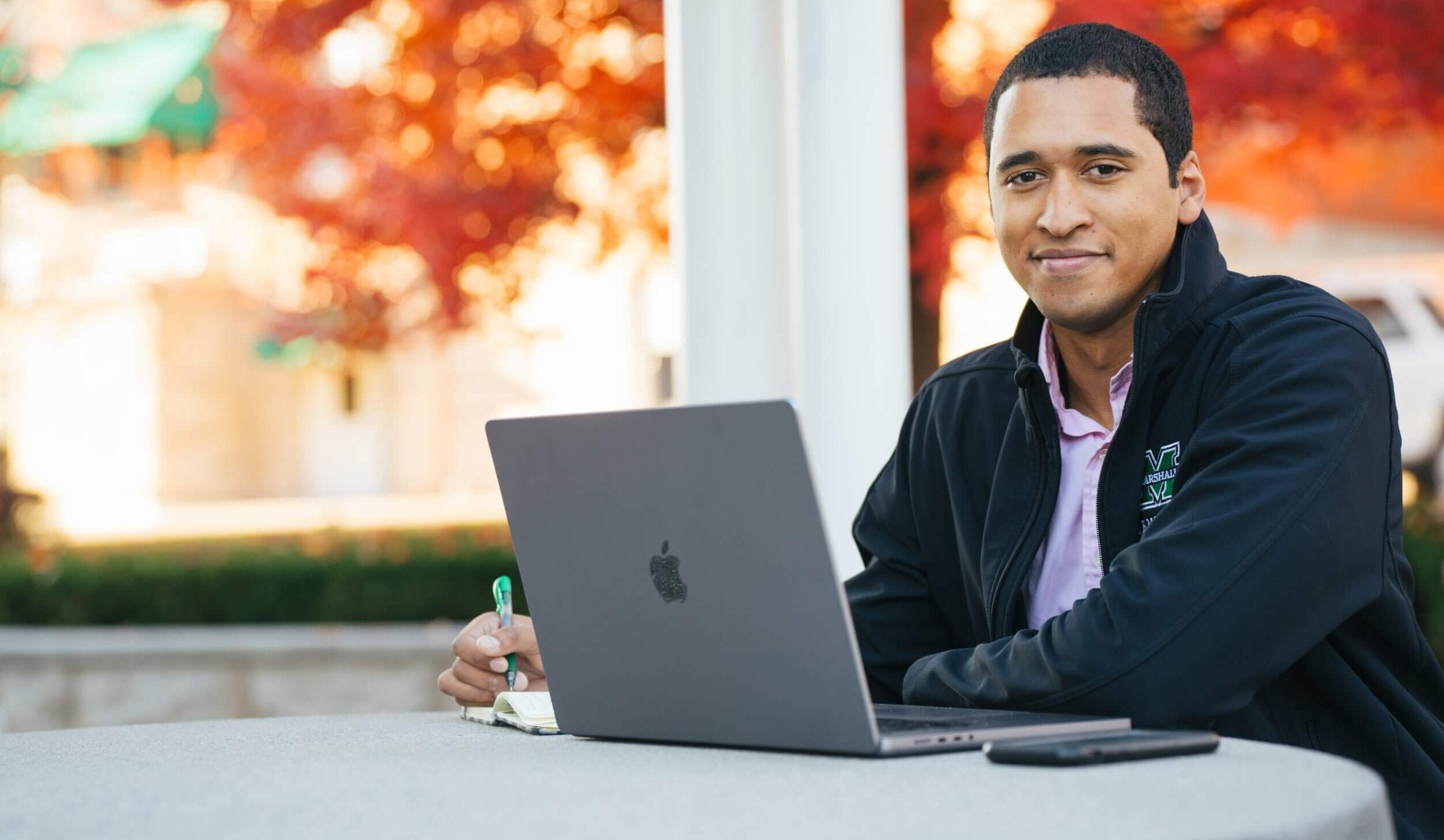 student outside working on a laptop during fall
