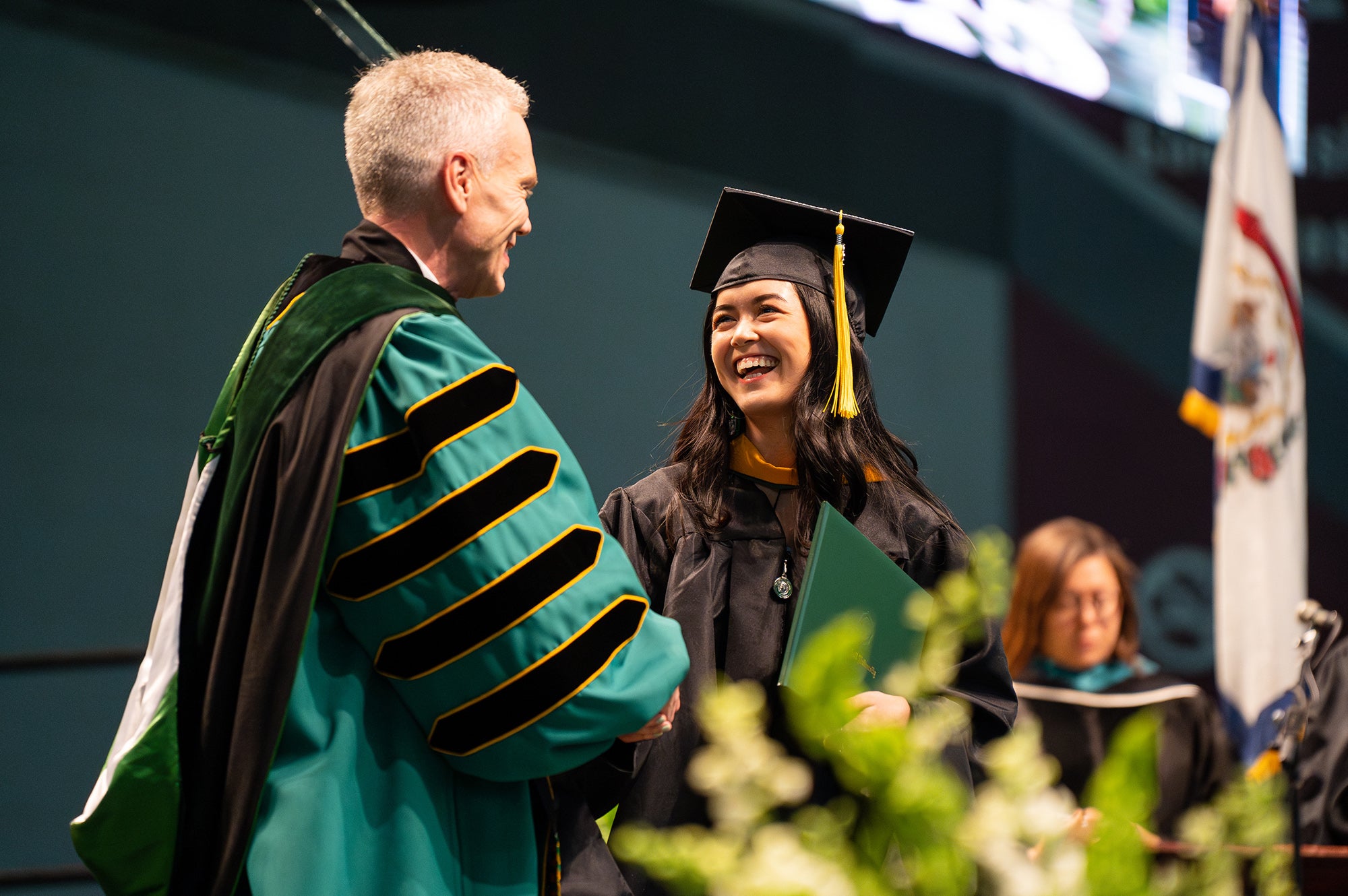 Brad D. Smith shakes a graduate's hand at Spring Commencement