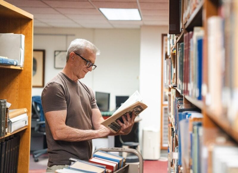 person reading a book in between library shelves
