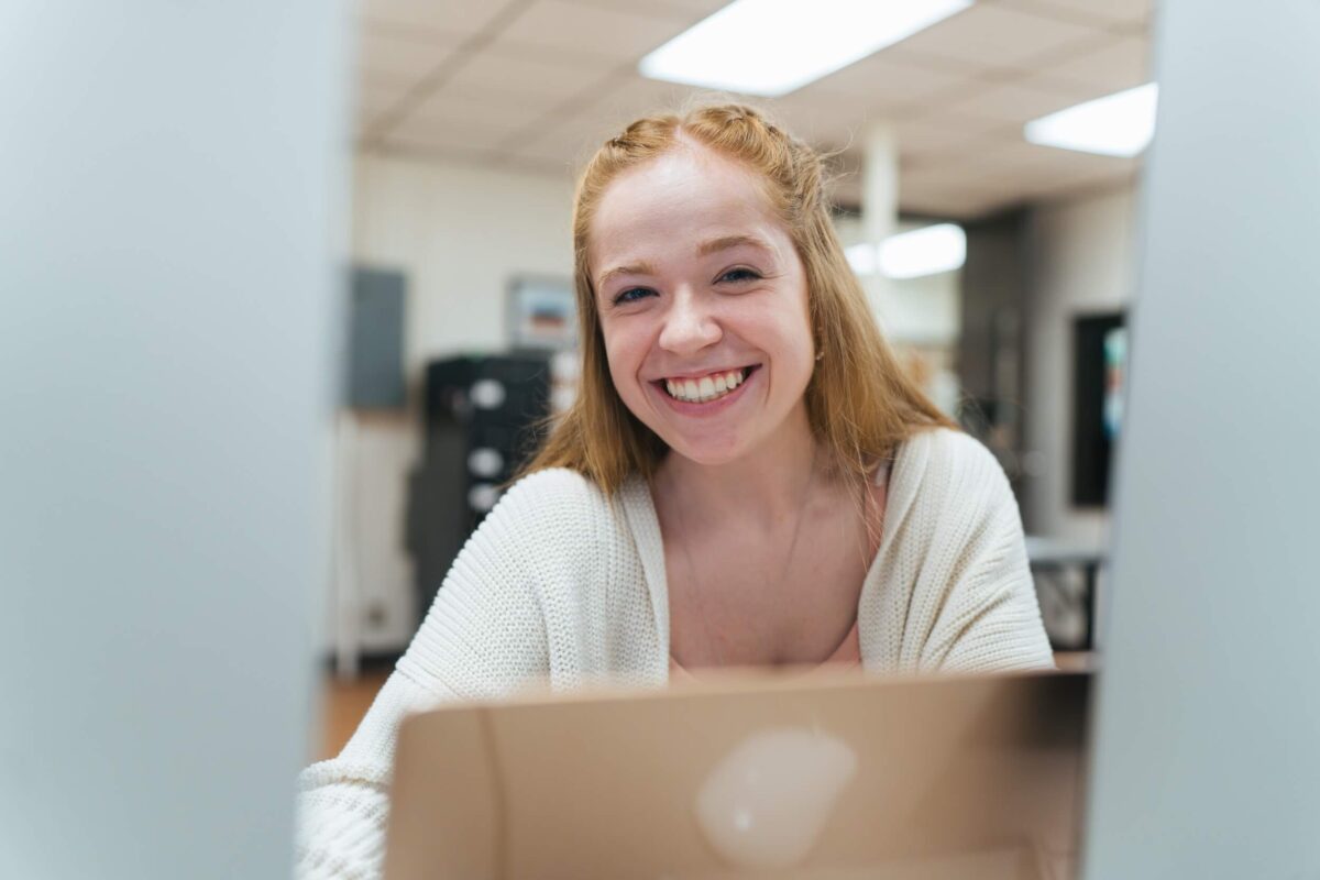 student working on a laptop in the student newspaper classroom