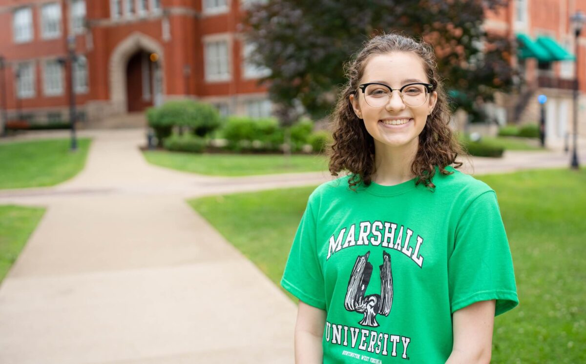student outside of Old Main smiling at the camera