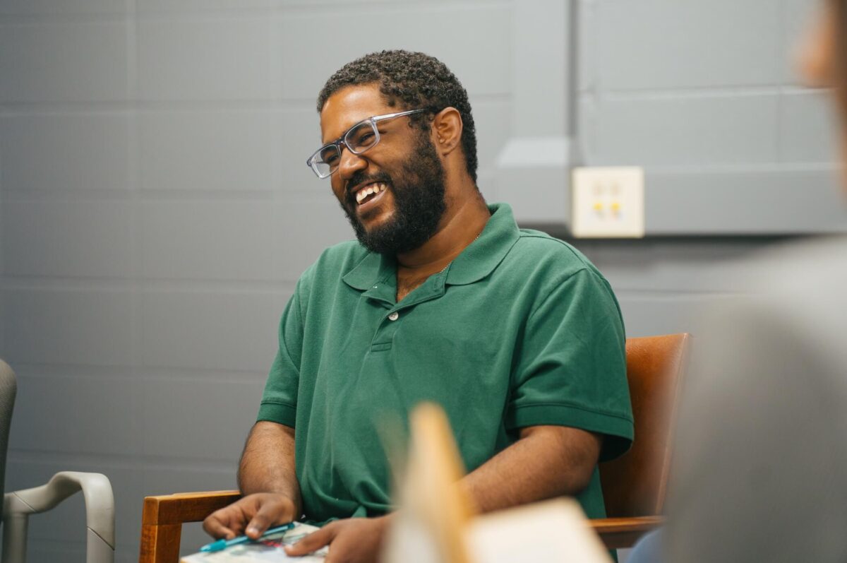 student holding a book and laughing off camera