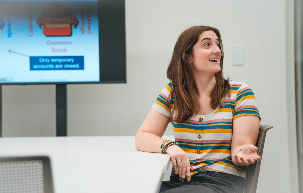 student sitting at a table talking to someone out of frame