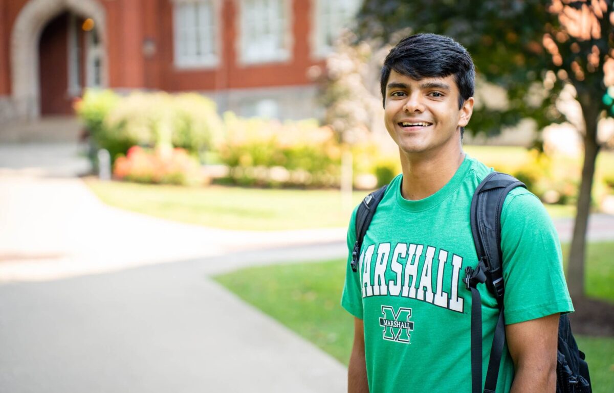 student standing outside of Old Main and smiling at the camera