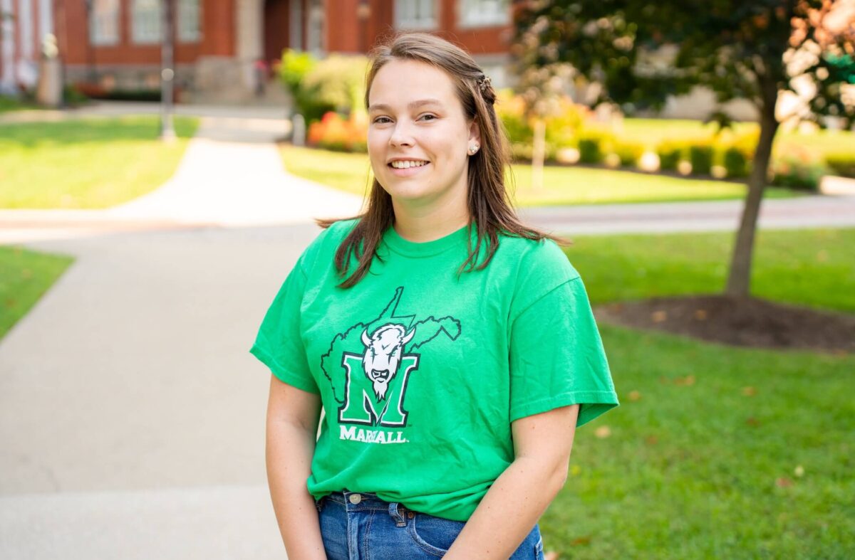 student outside of Old Main smiling at the camera