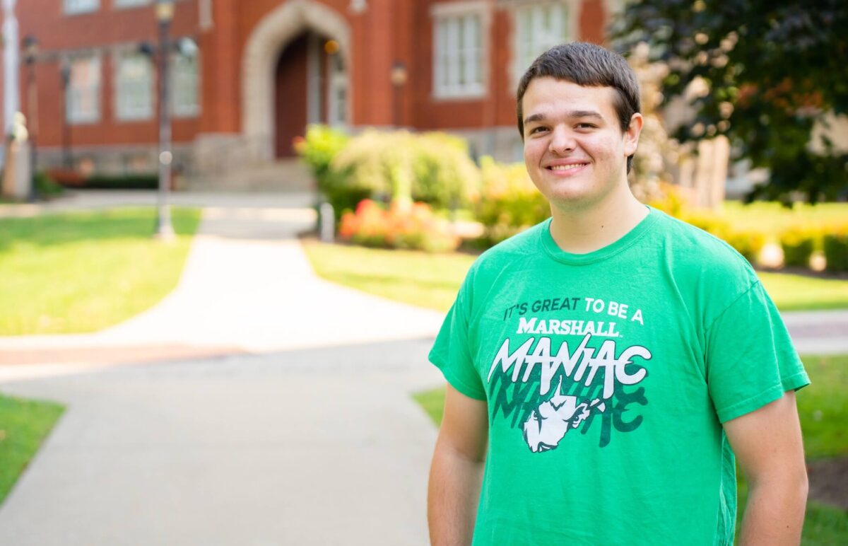 student outside of Old Main smiling at the camera
