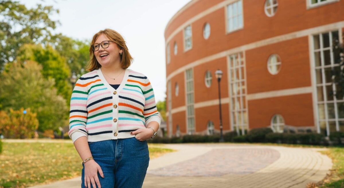 student outside Drinko Library smiling off camera