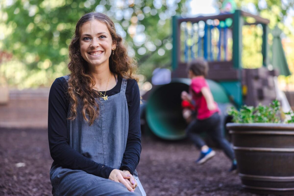student smiling at the camera sitting down on a playground