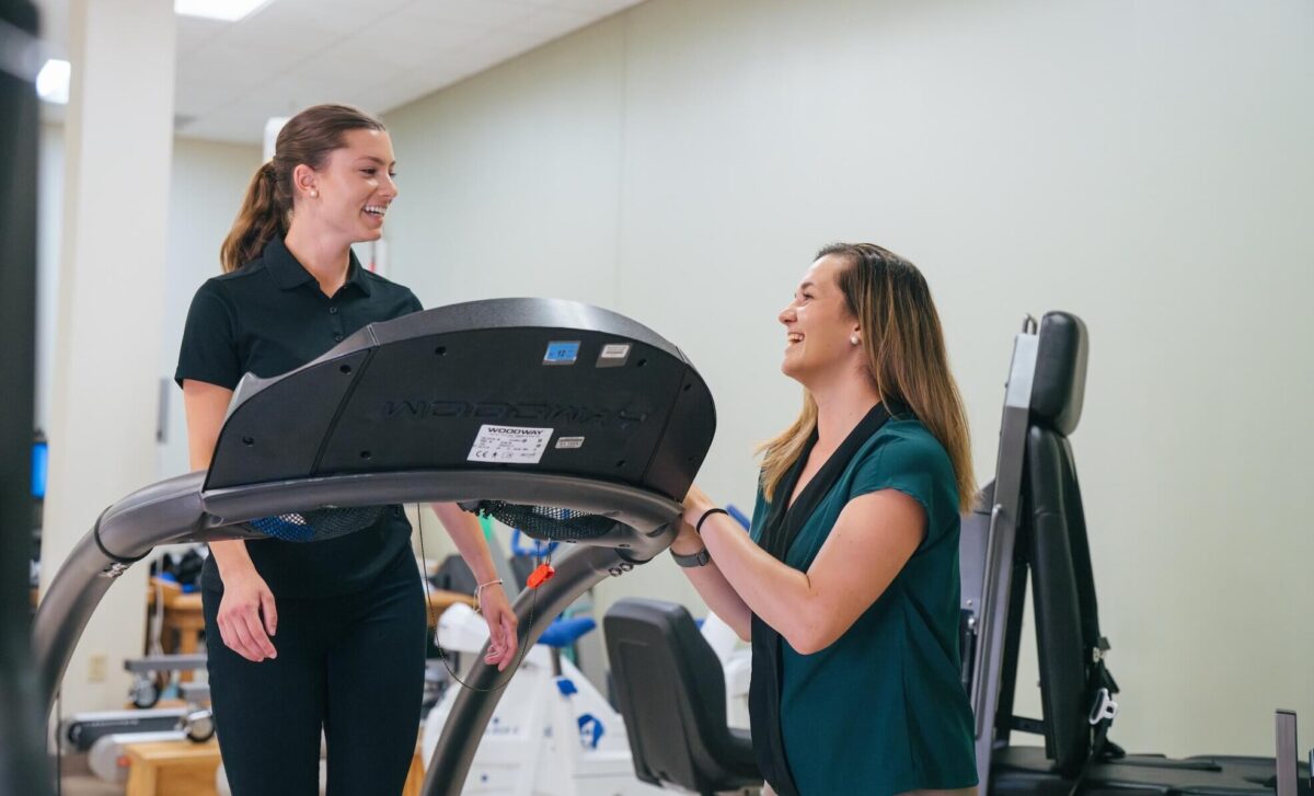 student walking on a treadmill with a professor supervising