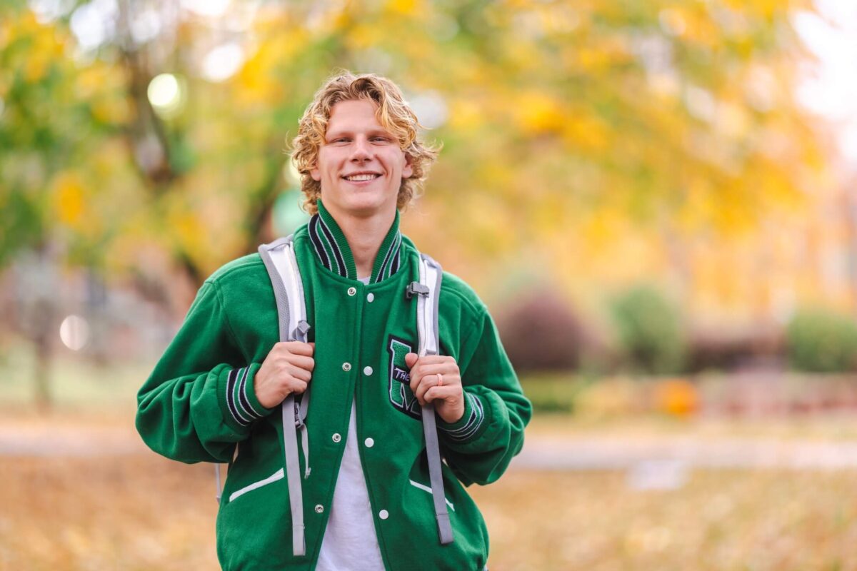 student outside on campus in the fall smiling at the camera