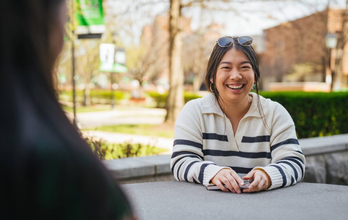 student outside Drinko Library smiling and laughing at the camera