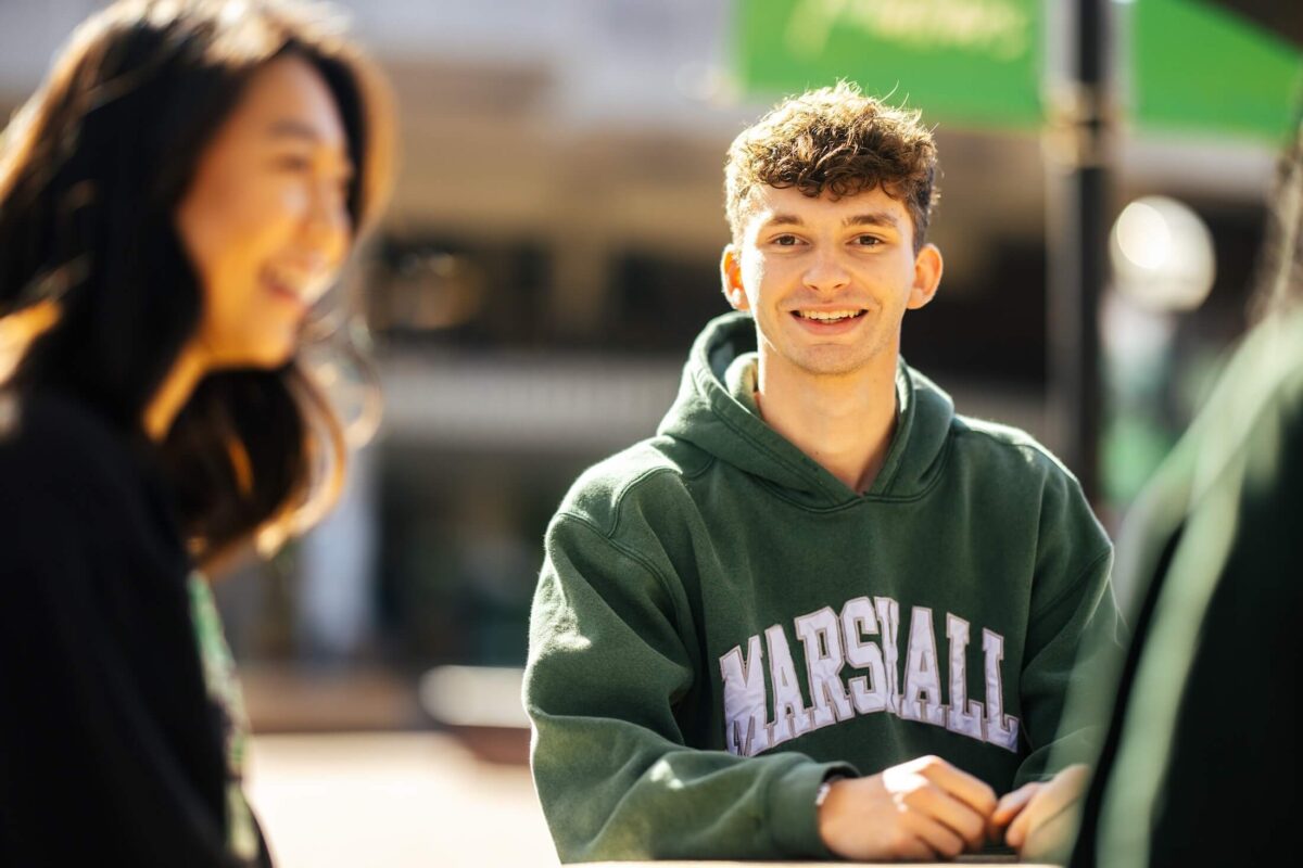 students talking outside the Memorial Student Center, one smiling at the camera