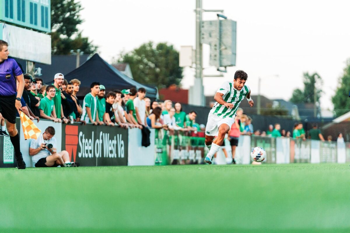 student playing soccer with large crowd watching