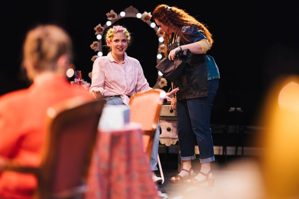 three students acting in a salon in a production of Steel Magnolias