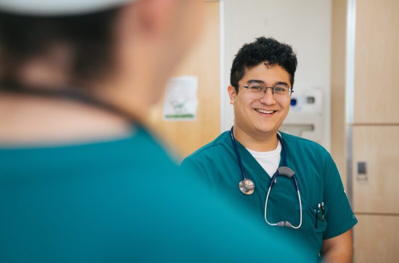 two nursing students in scrubs in a medical setting talking
