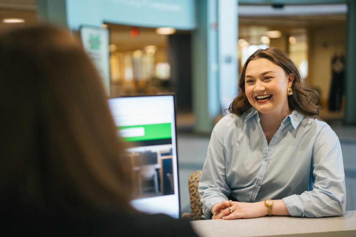 student talking to a staff member at a desk over a computer