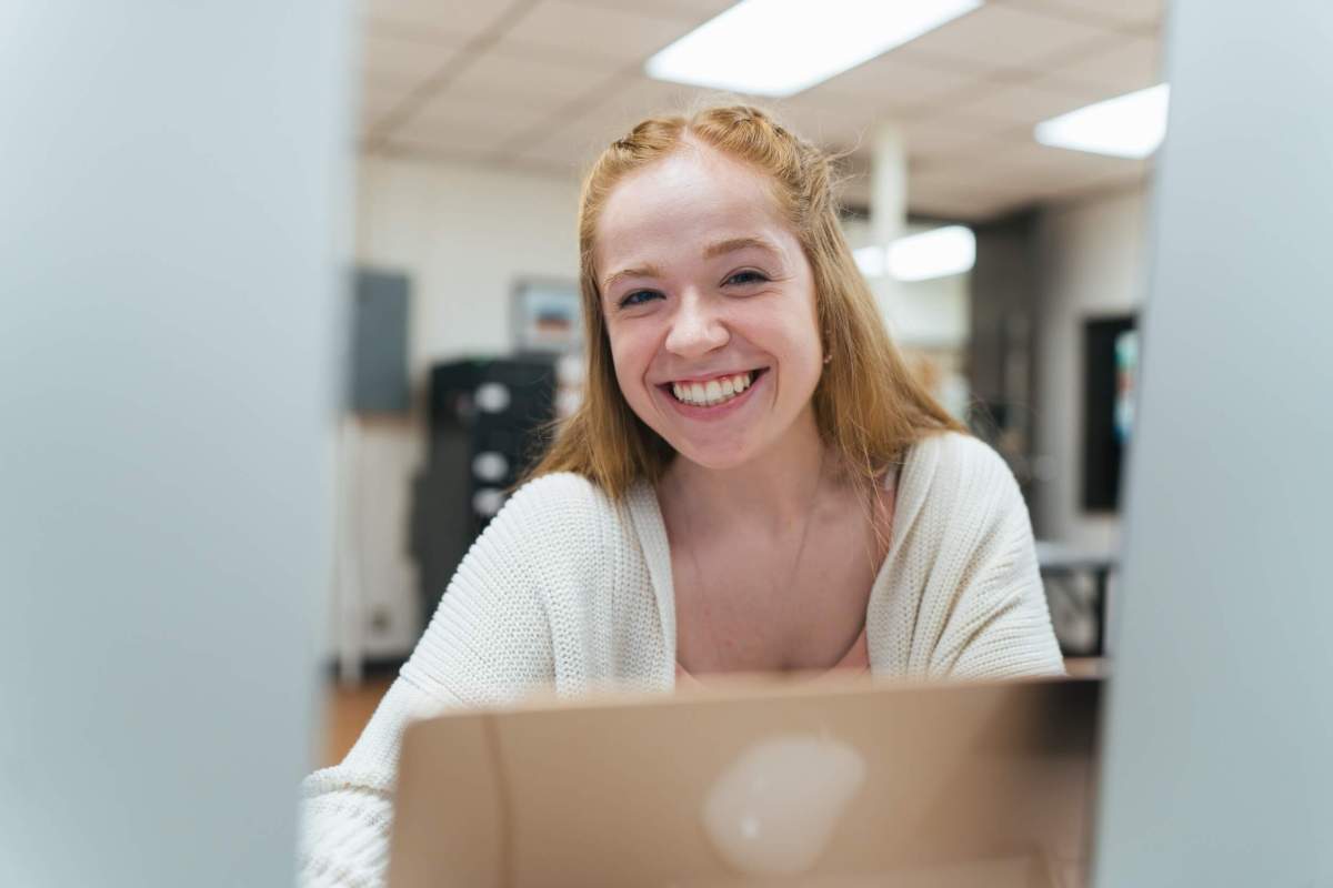student working on a laptop in the student newspaper classroom