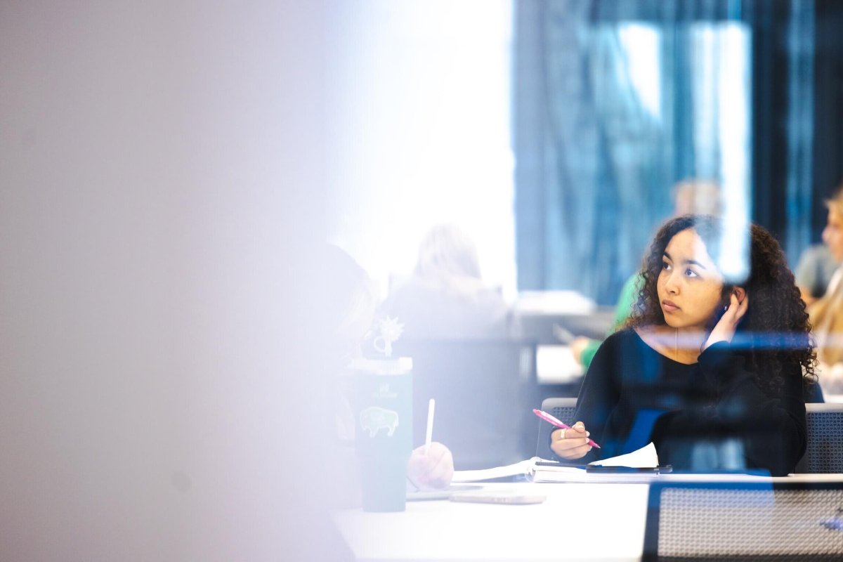 student taking notes in class through a window