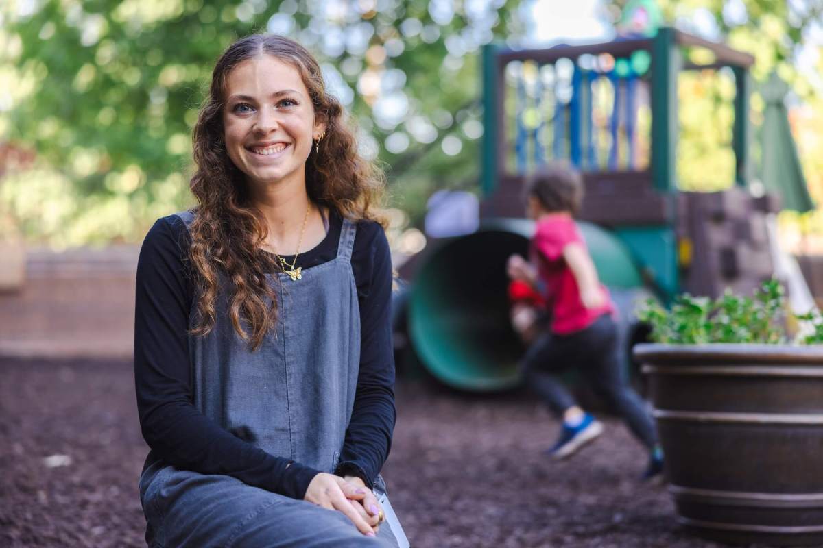 student smiling at the camera sitting down on a playground