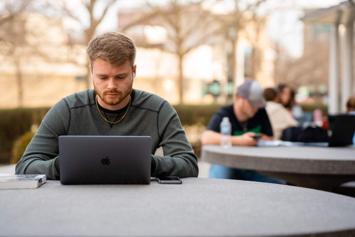 student working on a laptop outside Drinko Library