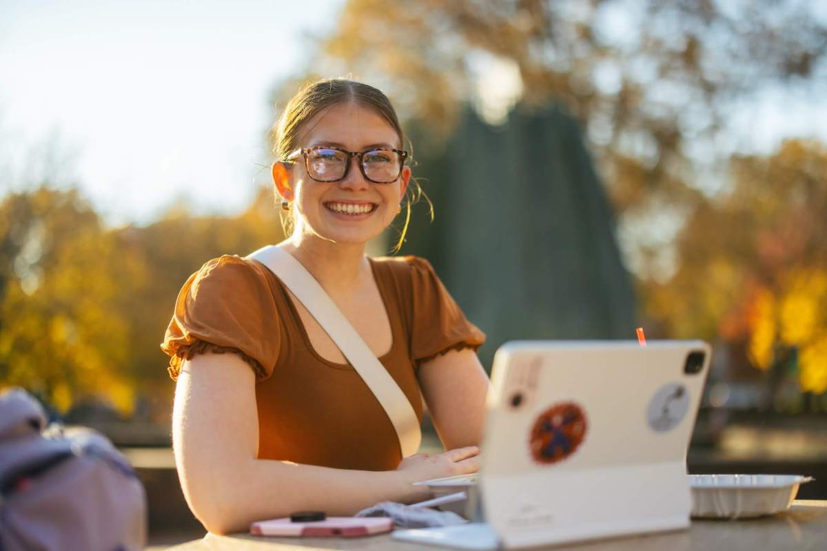 student working on an iPad outside by the Memorial Fountain