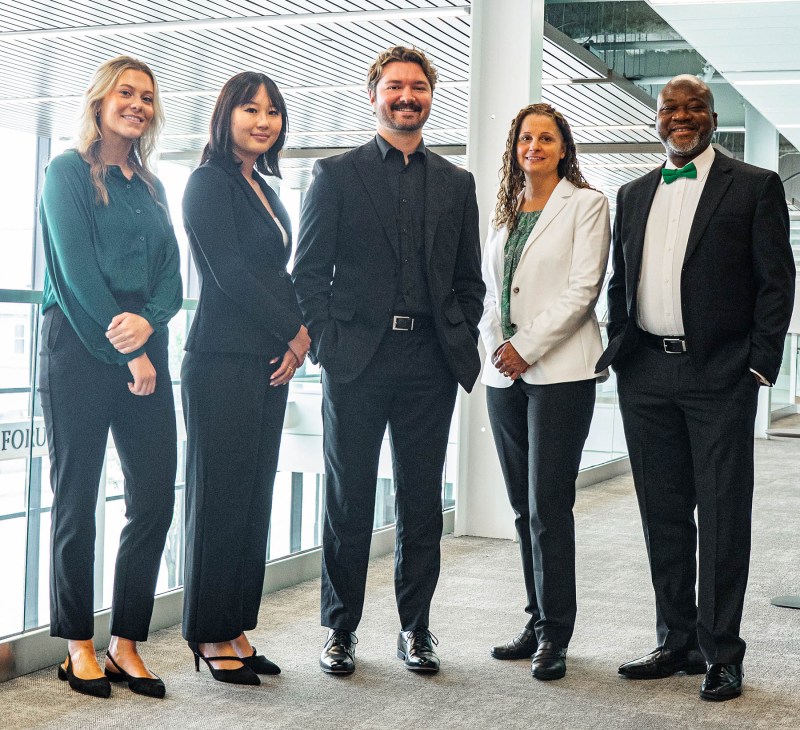 A group of business students stand together wearing professional attire