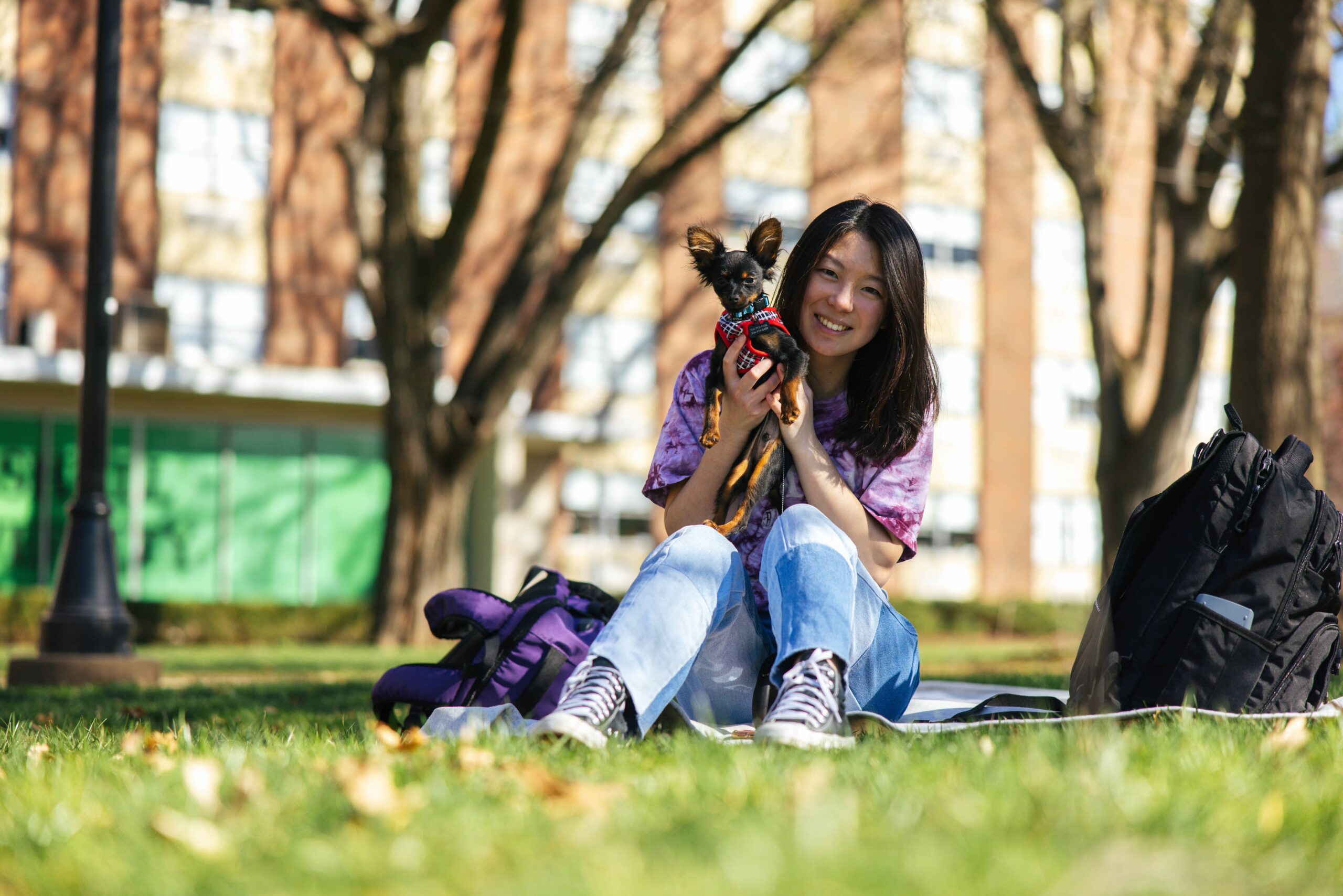 A student smiles with a support dog on Marshall University's Buskirk field