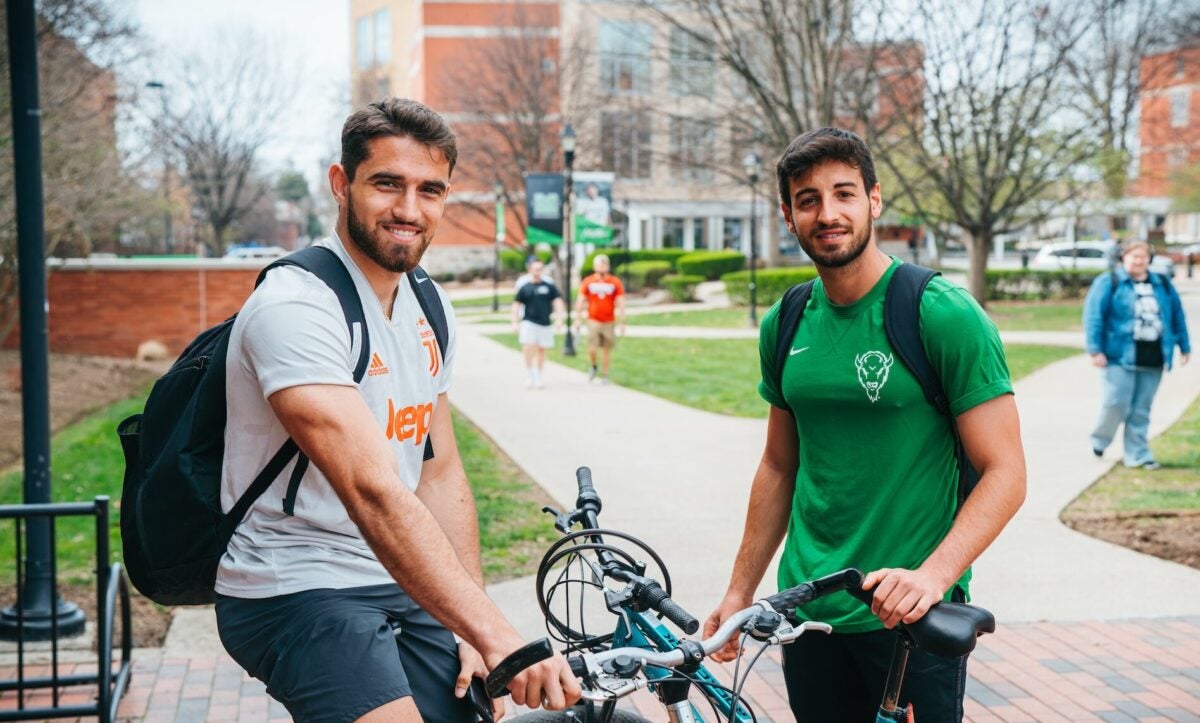 two students outside with bicycles