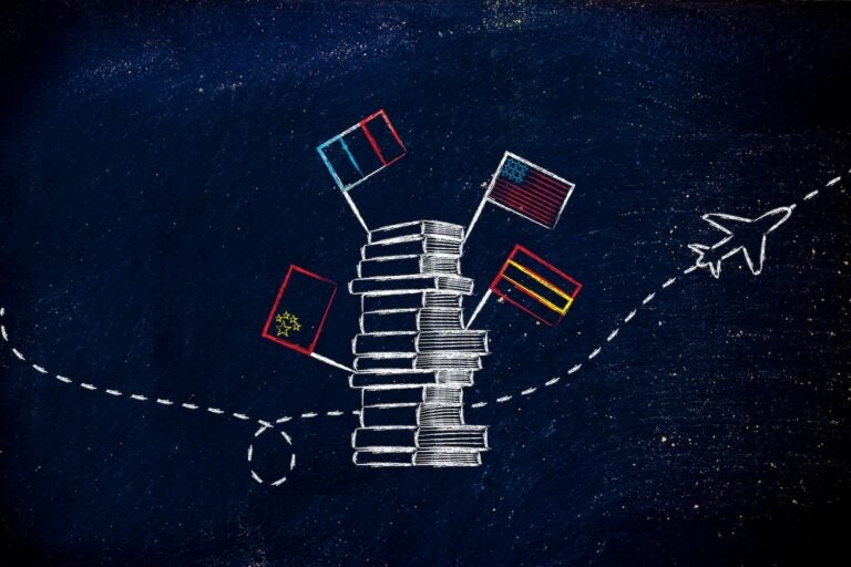 pile of books with flags and airplane flying in the background, studying foreign languages