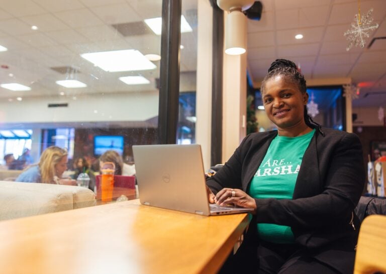 student sitting at a desk at starbucks on campus and working on a laptop