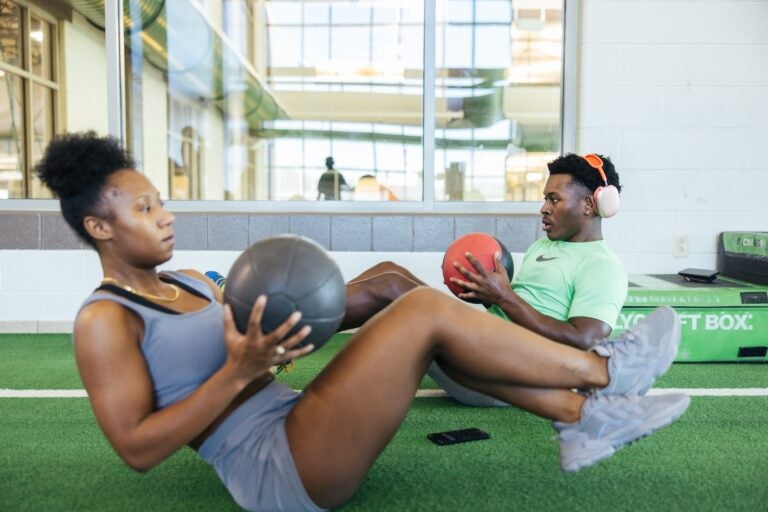 two students doing an ab work out at the rec center with medicine balls