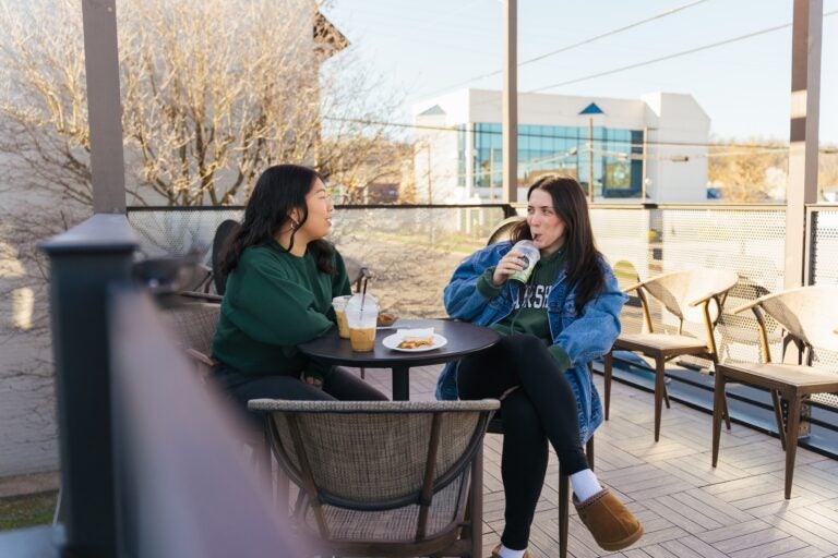 two students drinking coffee at Grindstone Coffeeology