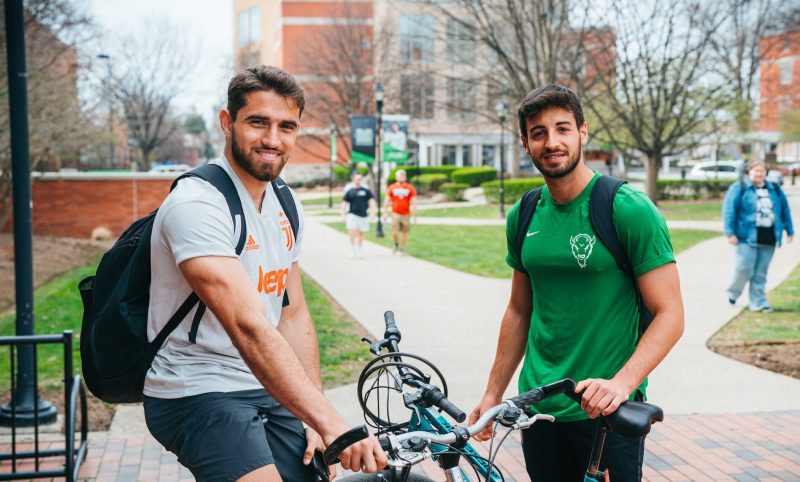 two students outside with bicycles