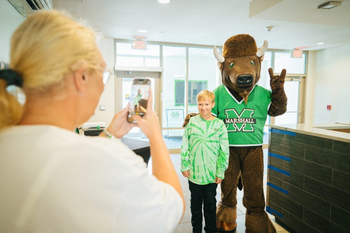 child with Marco and person taking a photo of them on a phone in the foreground